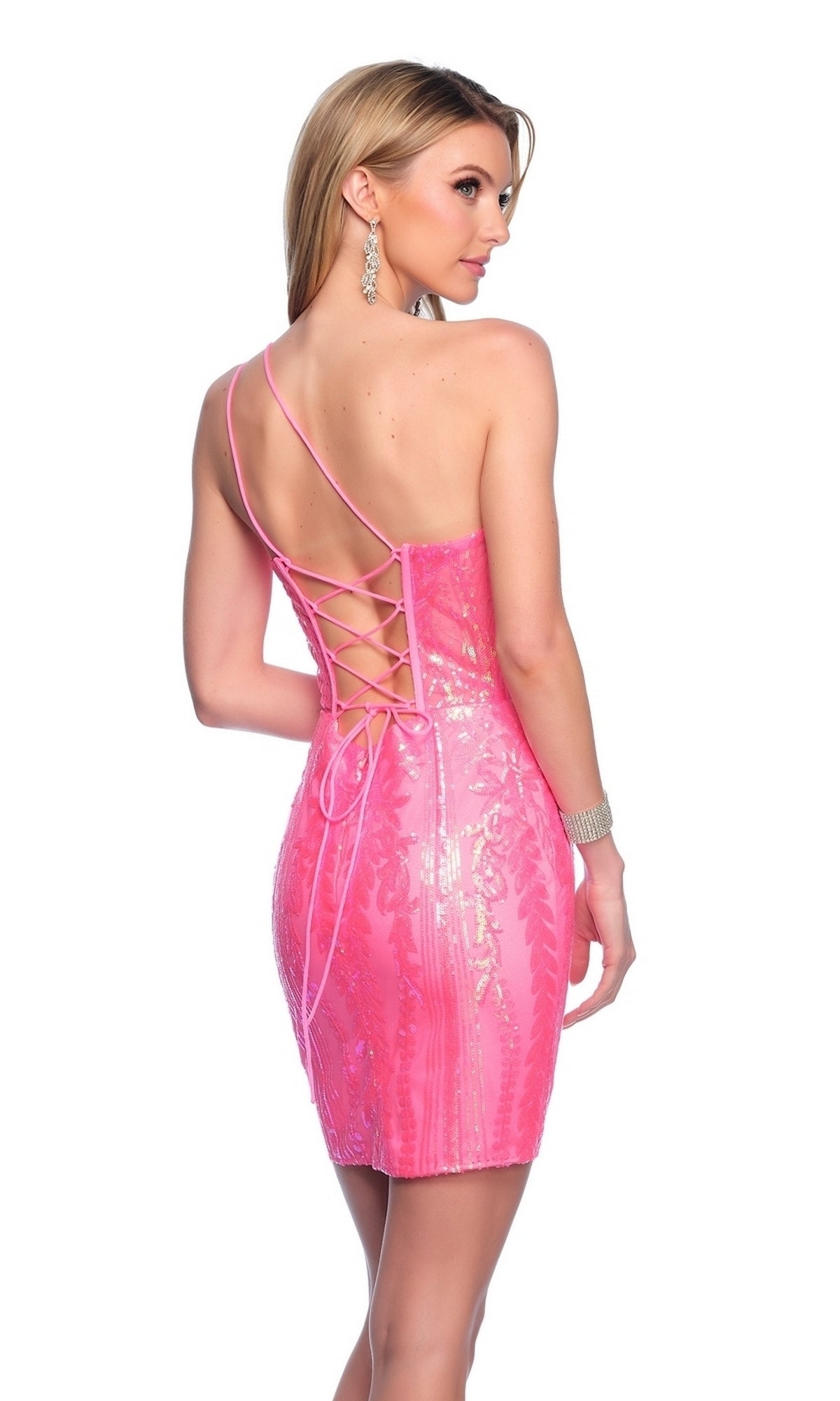 Woman in the Dave & Johnny Short Pink Sequin Hoco Dress 11889, featuring a shiny, fitted design with thin straps and a lace-up back, stands looking over her shoulder.